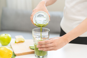 Detox juice concept, Hand of woman, girl holding bottle making green vegetable smoothie pouring in...