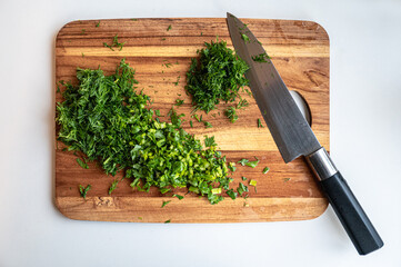 Freshly chopped herbs on a wooden cutting board with a chef's knife.