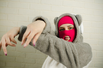 Woman in pink Balaclava Dancing Against a White Brick Wall