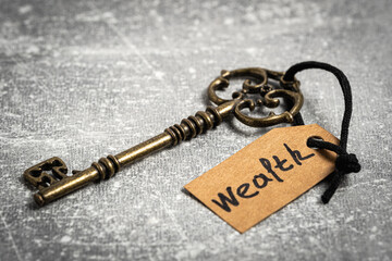 Vintage key with tag and inscription wealth. Concept is key to success.