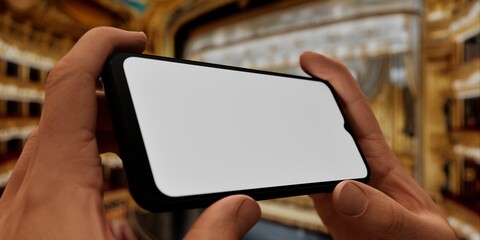 Hand holding a phone with a blank screen against a theater backdrop