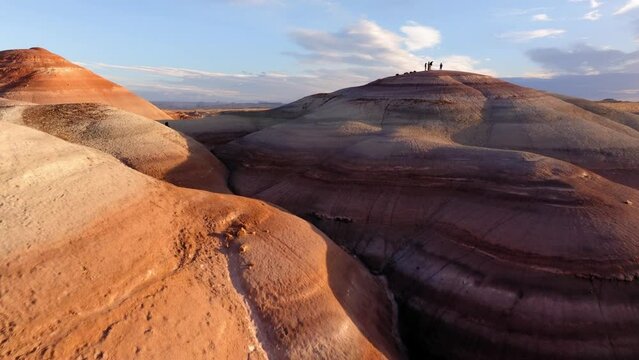 Aerial Forward Shot Of People On Top Of Bentonite Hiking Hills Under Cloudy Sky - Moab, Utah