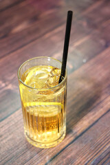  A cold drink with lemon and ice in a glass on a wooden table