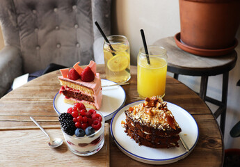 berry desserts and chocolate cake on a wooden table in the interior of the room