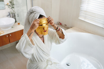 Woman applying golden moisturizing face mask