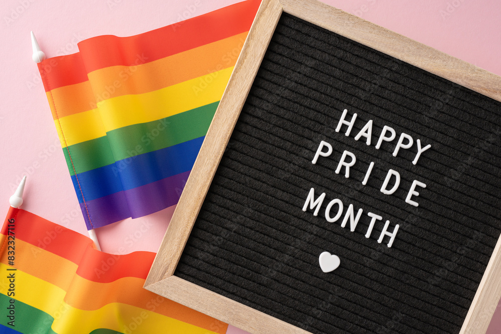 Wall mural happy pride month message displayed on a letter board with two rainbow flags on a pink background ce