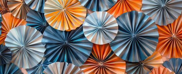 Abstract paper fans in various shades of orange, blue and grey are arranged to create an intricate pattern. The fans are arranged in the style of pointillism to form an abstract design.