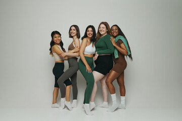 Naklejka premium Portrait of women of different ethnicities and body types pose in fashionable activewear against white studio background. Concept of beauty and fashion, support, unity, wellness, body positivity.