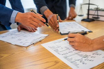 A team meeting of business people and a lawyer in formal suits is taking place at a desk,...