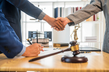 A team meeting of business people and a lawyer in formal suits is taking place at a desk,...