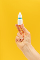 White bottle of medical drops in a hand