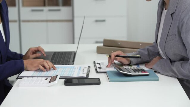 Two Asian businesswomen collaborate on stock market strategies and financial services, exchanging comments and suggestions on loan applications and investment opportunities.