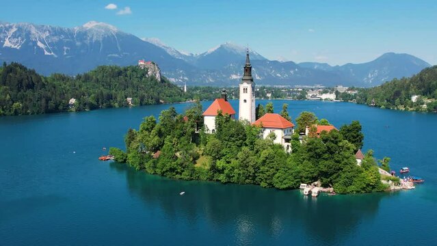 Pilgrimage Church of the Assumption of Mary In Lake Bled, Slovenia. Summer blue lake and mountains in background. Orbiting shot.
