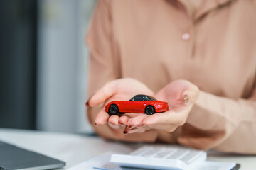 Fototapeta premium Asian businesswoman negotiates the sale of a car, discussing insurance and financing options, used car loans, premiums, deductibles, and various coverage types to ensure comprehensive protection.