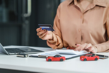 Fototapeta premium Asian businesswoman negotiates the sale of a car, discussing insurance and financing options, used car loans, premiums, deductibles, and various coverage types to ensure comprehensive protection.