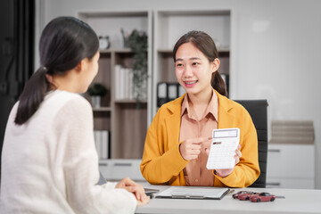 Asian businesswoman and a salesman discuss car sales, insurance, and financing with a customer at a desk, covering used car loans, premiums, deductibles, and various insurance coverage options.