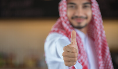 A Saudi Arabian man in traditional dress giving a thumbs up.