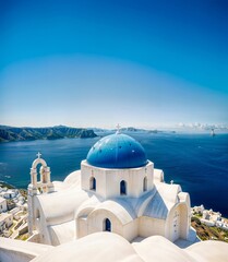 A white church with blue domed roofs overlooking the sea and islands in the distance, set against a clear blue sky