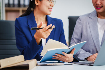 Two Asian businesswomen collaborate on stock market strategies and financial services, exchanging...