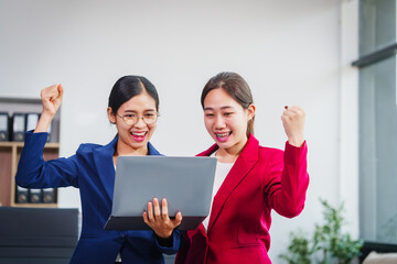 Two successful Asian businesswomen collaborate, discussing comments and suggestions on various...