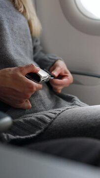 Close-up Woman Fastening her seat belt on an airplane