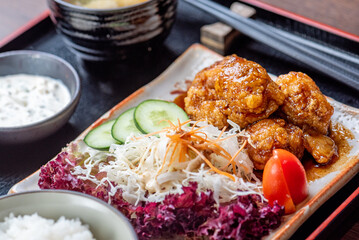 A plate of Japanese fried chicken with rice, salad, and miso soup.