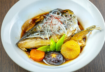 A plate of boiled fish head with vegetables.