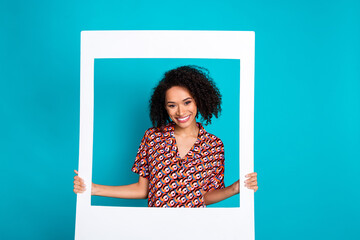 Photo of positive cheerful lady hold white photo frame isolated cyan color background