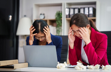 Two Asian businesswomen under stress and pressure discuss financial matters, experiencing anxiety...