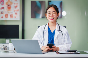 Asian female doctor specializes in psychiatry, providing online consultations and psychotherapy from her desk. She offers diagnosis, treatment, counseling, and medication for mental health disorders.