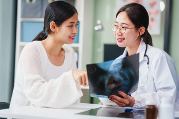 Asian female doctor specializing in psychiatry works at her desk, providing psychotherapy, diagnosis, treatment, and counseling to psychiatric patients, utilizing x-ray films for assessments.