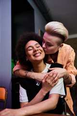 Lesbian couple sharing a loving hug while seated at a cafe table.