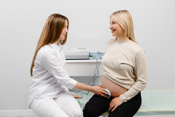 Doctor prepares a pregnant woman for checking fetal heartbeat by fetal monitoring.