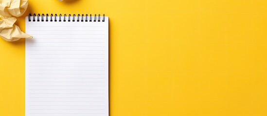 Top down copy space image of a yellow background with a notebook pen and crumpled paper representing the concept of writer s block