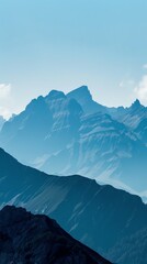 Serene mountain landscape with misty blue hues and majestic peaks under a clear sky, perfect for nature and travel themes.