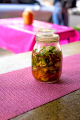 Glass container with pickles to accompany the pupusas.