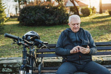 Man Sitting on Bench Using Cell Phone in a Park