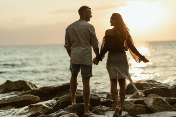 Man and Woman Standing Holding Hands on the Sunset Beach