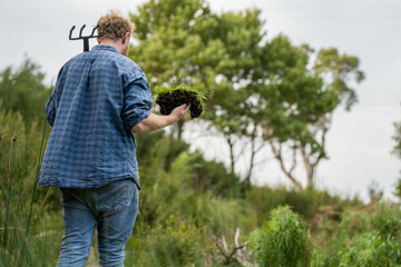 Fototapeta premium university student conducting research on forest health. farmer collecting soil samples in a test tube in a field. Agronomist checking soil carbon and plant health on a farm in australia