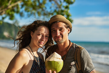 Travel, portrait and couple with cocktail by beach for outdoor adventure, romance and tourist...