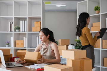 Two businesswomen organizing and preparing packages for shipping in office. Concept of e-commerce...