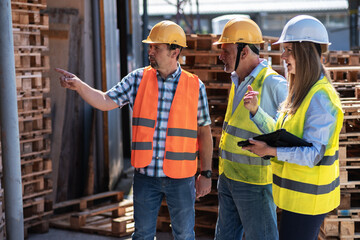 Wooden industry workers walk with their supervisor on the factory yard, checking numbers and...