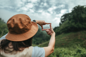 Hands of woman traveler making frame gesture with mountains and forest, Rest on vacation holiday...