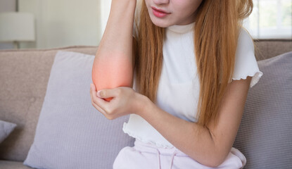 Close up Asian woman suffering from elbow pain at home. Concept of physical discomfort, pain...