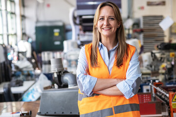 The portrait of a female supervisor stands confidently on the factory line, overseeing the production process. © BalanceFormCreative