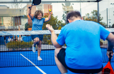 Female adult padel player celebrates victory in game on outdoor court.