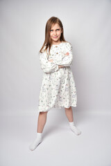 Full length portrait of a kid girl standing with crossed arms, white background