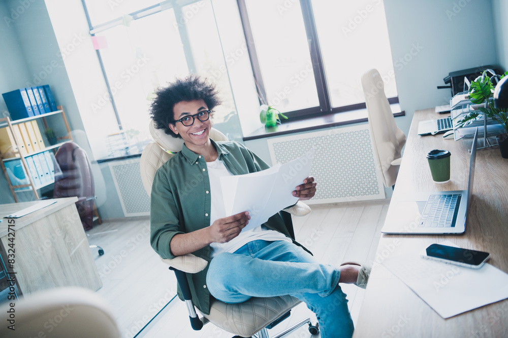 Sticker Photo of cheerful handsome agent dressed khaki shirt eyewear reading documents indoors workshop workstation