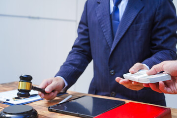Hands of Asian and African male lawyers working with contract documents and wooden gavel on table in courtroom. Court judges and lawyers