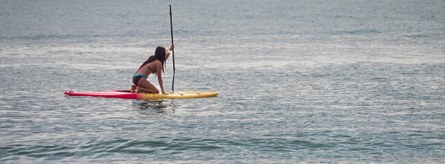 Young beautiful woman sitting on paddleboard surfer on a beautiful sunny day